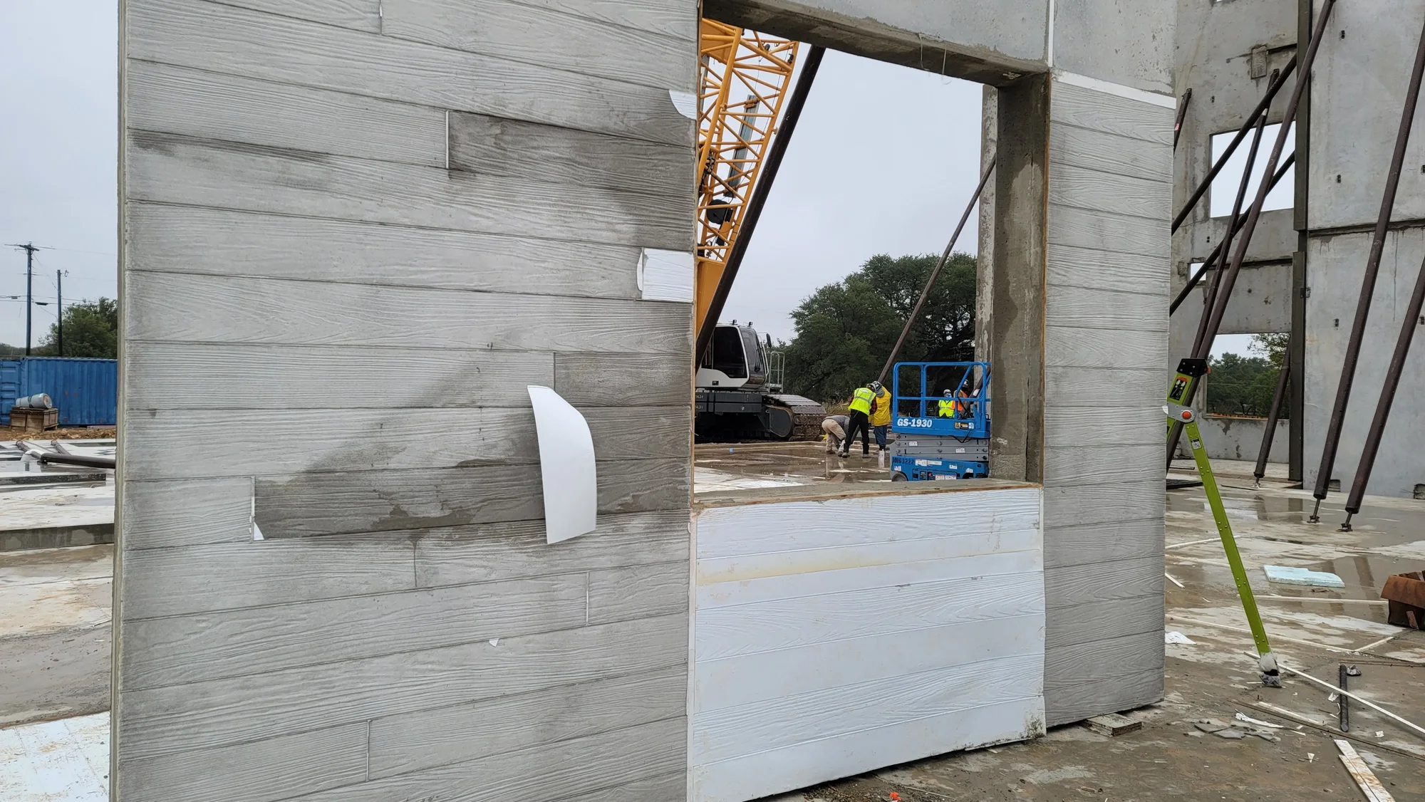 Tilt-up panel with board-form wood texture being lifted on site